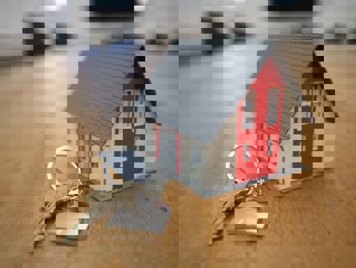 Miniature house and a key on a keychain on a brown wooden table